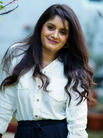A classic portrait of a woman in a simple white shirt, looking directly at the camera with a serene expression.