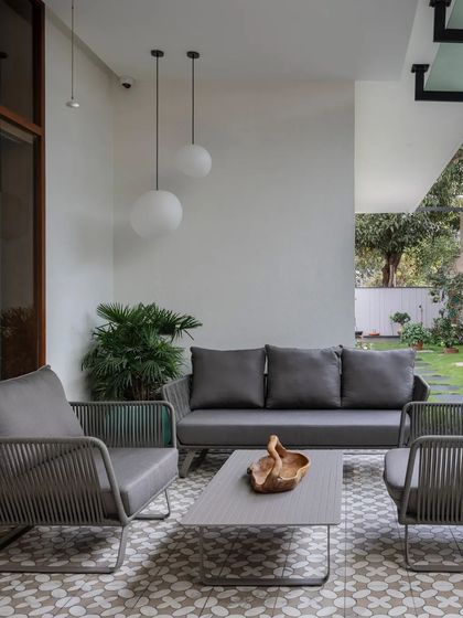 An outdoor patio with modern grey furniture and patterned tiles provides a chic and comfortable space for enjoying the garden.
