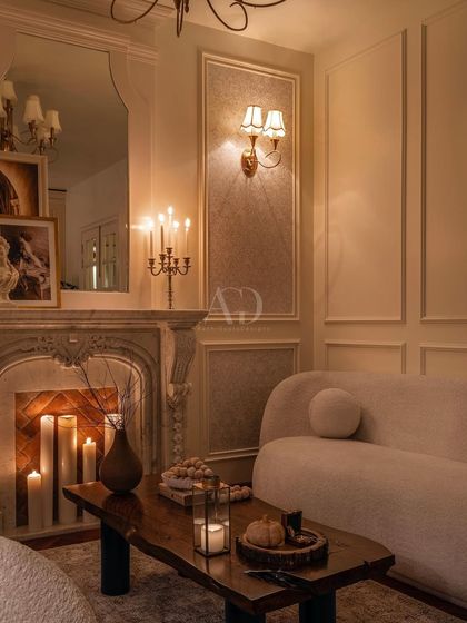 A beautifully composed shot of the fireplace area, where the mirror reflects the room's chandelier and adds depth. The arrangement of furniture and decor feels both deliberate and effortlessly elegant.