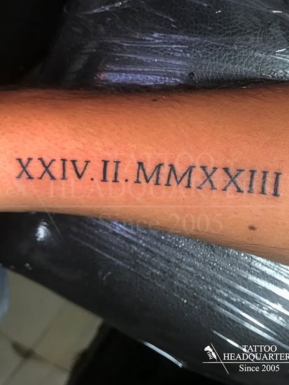 A significant date, "XXIV.II.MMXXIII" (February 24, 2023), tattooed in Roman numerals.