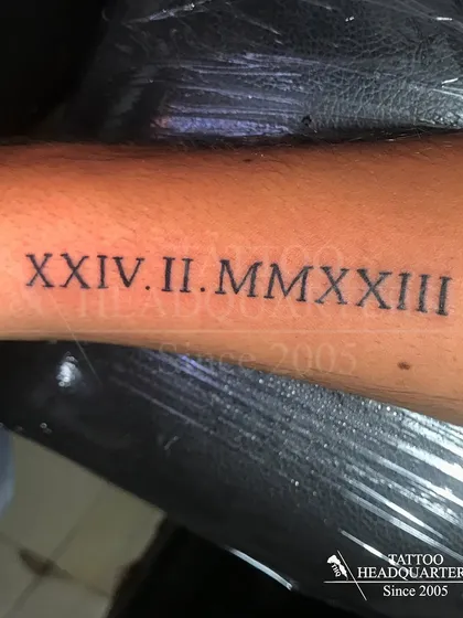 A significant date, "XXIV.II.MMXXIII" (February 24, 2023), tattooed in Roman numerals.