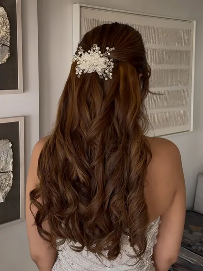 A classic half-up style with soft waves, adorned with a beautiful white and pearl hair accessory, perfect for a Christian wedding or a white-themed party.