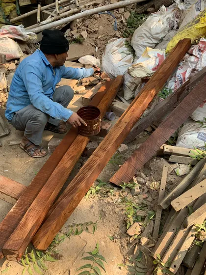 A craftsman applying a finish to reclaimed wood on-site, an example of our commitment to circular design and reusing historic materials.