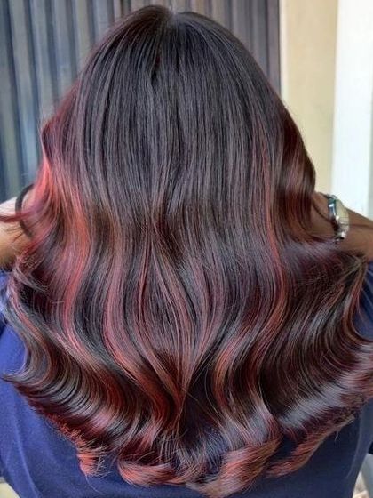 This back view highlights the seamless blend of red and brunette tones. Our training covers advanced blending methods to ensure a flawless and professional color melt.