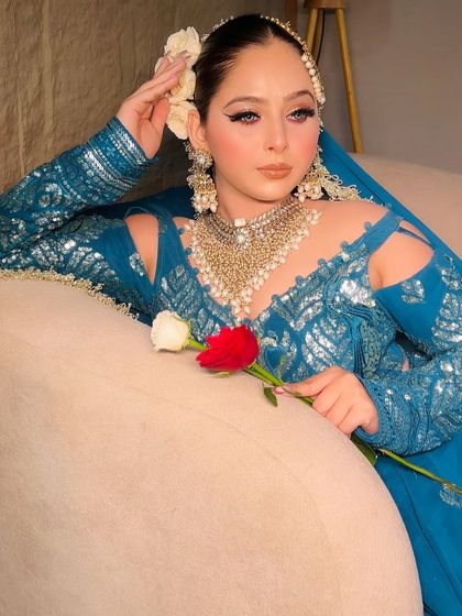 A romantic shot of the model with a rose, wearing the teal blue lehenga.