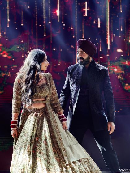 Simranjeet and Bimaljeet on their Sangeet stage, the dramatic lighting creating a glamorous and powerful portrait.