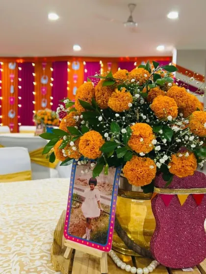 A traditional table centerpiece featuring a brass pot filled with bright orange marigolds. We added a personal touch with a childhood photo of the mom-to-be, making the decor more meaningful.