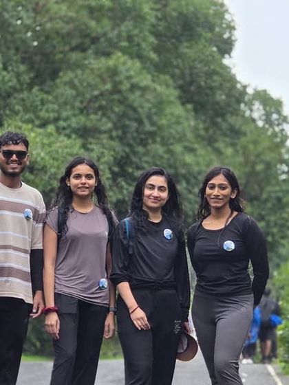 A group of friends posing for a photo on the road leading to the Kurinjal trek start point, with lush greenery all around.
