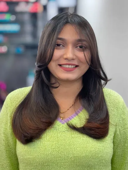 A smiling client showing off her new layered haircut. It's a look that's both professional and fun.