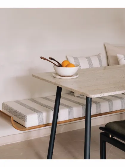 Inspired by the minimalist Wabi-Sabi aesthetic, this dining space features a sleek bench-style seating. The simple Indian marble top table and striped cushions create a look that is clean, intentional, and beautifully understated.