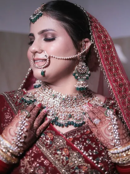 The focus here is on the stunning bridal jewelry and how the makeup enhances it. The soft, shimmering eyeshadow and contoured cheeks complement the heavy kundan and emerald necklace beautifully.