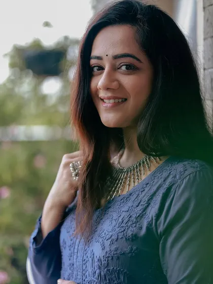 A soft, smiling portrait of Spruha Varad in the blue kurta.