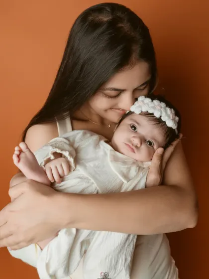 A tender moment between a mother and her newborn daughter. The simple, clean background keeps the focus on her sweet expression and the loving embrace.