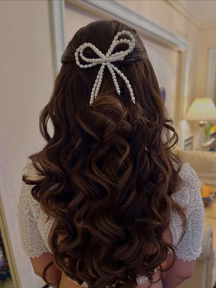 A chic half-up style featuring a large bow made of pearls, adding a touch of modern elegance to the soft curls.