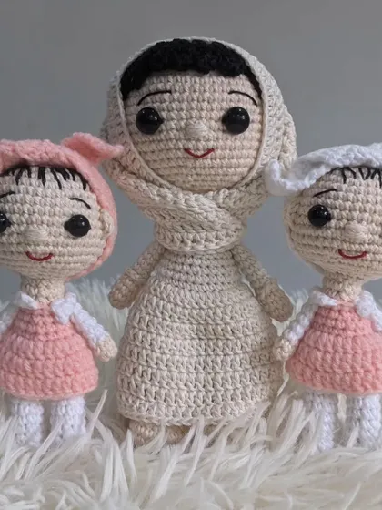 A mother and her two daughters, crafted as a custom crochet set. The matching pink dresses on the little girls add a sweet touch.