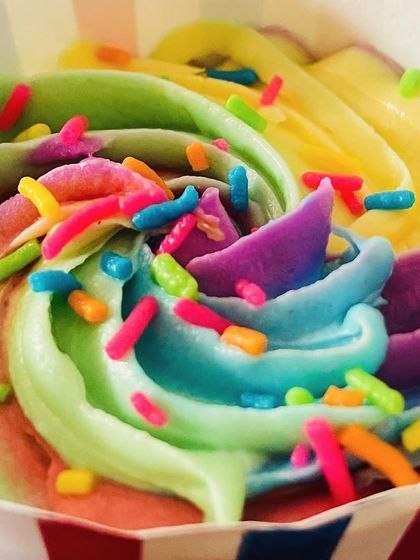 An overhead close-up of the beautiful frosting on our rainbow cupcake, showing the blend of green, yellow, blue, and purple hues.