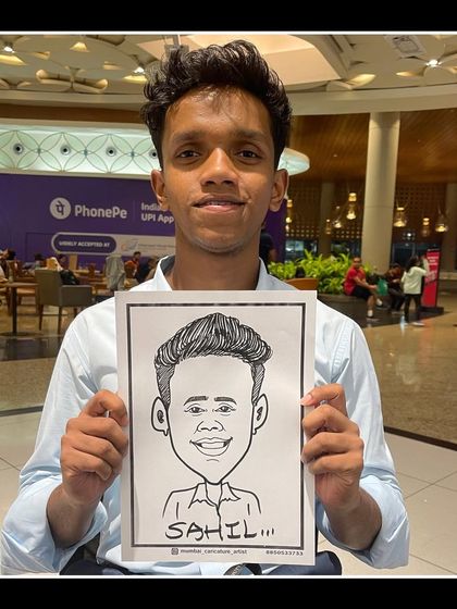 A young man with his caricature, drawn at a public event in Mumbai.