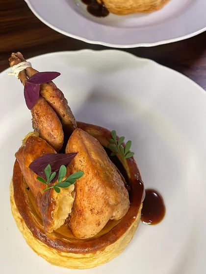 The final plating of the Caille En Sarcophage, with the pan-roasted quail pieces arranged back in the vol-au-vent with a marjoram jus.