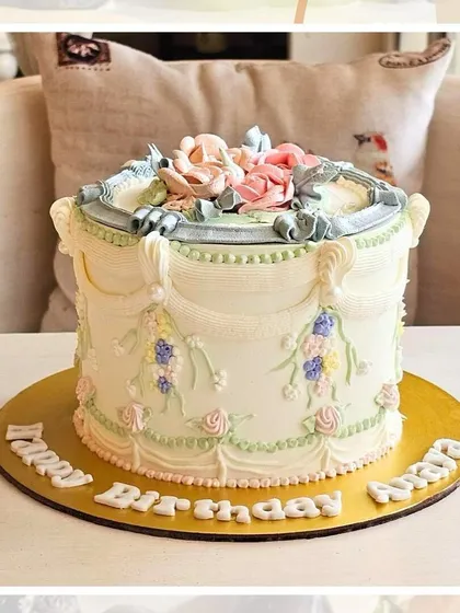A vintage-style cake with intricate Lambeth piping in pastel blue and pink, creating a classic and ornate design.