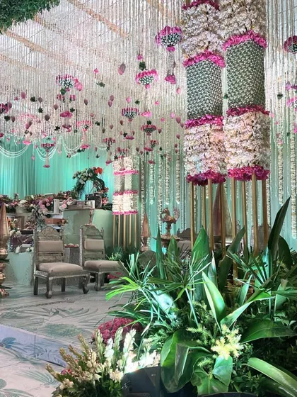 The full view of a breathtaking engagement stage. The ceiling is a cascade of floral strings, and the stage is adorned with silver chairs and lush greenery, creating a pastel paradise.