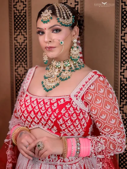 A confident portrait of the bride looking directly at the camera, set against a patterned indoor background.