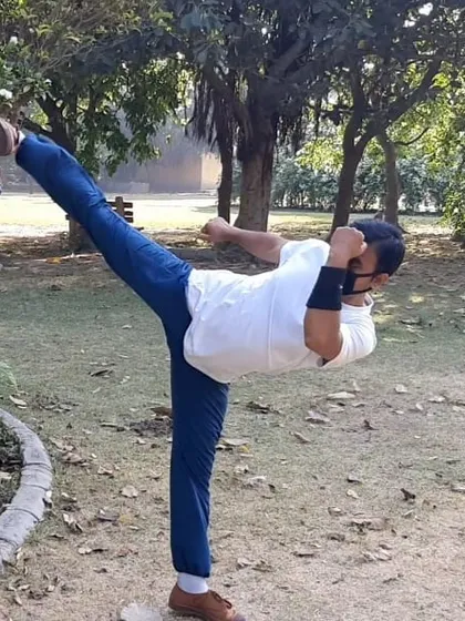 A high side kick performed during an outdoor training session. Practicing on different surfaces helps improve balance and adaptability, making your martial arts skills practical in any environment.