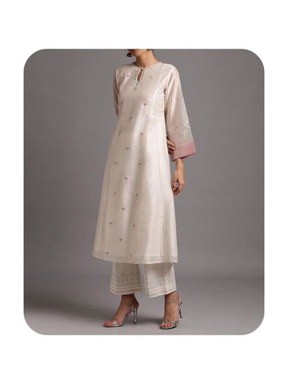 An elegant off-white A-line kurti in a chanderi or silk fabric with delicate embroidery. The contrasting pink cuffs add a subtle pop of color. I can tailor similar pieces for a sophisticated and understated look.