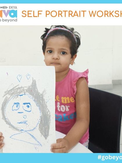 A young girl proudly holds up her expressive self-portrait. The simple lines and colors capture a unique personality, showcasing the power of art for self-expression, even at a very young age.