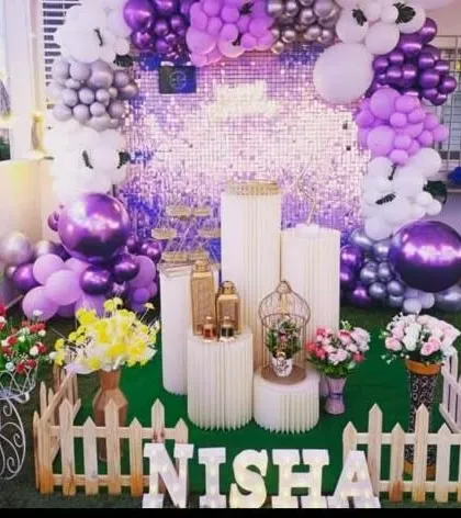 A lavish purple and silver decoration with a sequin wall, extensive balloon work, and fresh flower arrangements.