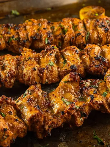 Freshly grilled chicken tikka on skewers, glistening and ready to serve. This close-up for Punjab Grill highlights the texture and char marks.