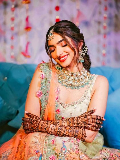 A stunning professional shot of a bride, her eyes closed in a moment of bliss, with her beautiful mehandi framing her face.