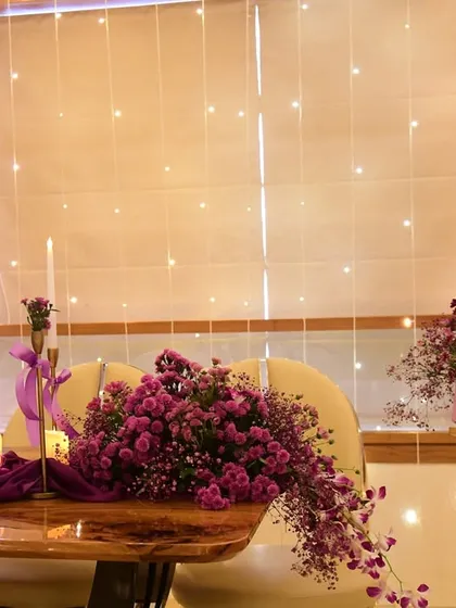 The full view of our purple-themed birthday setup, including the tablescape, a custom welcome board, and a beautiful floral arch, all under a ceiling of twinkling fairy lights.