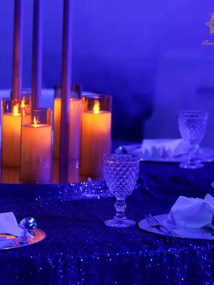 Tablescapes were kept modern and elegant to complement the theme. Tall, minimalist candle holders cast a warm glow against the cool blue, sequined tablecloths and crystal glassware.