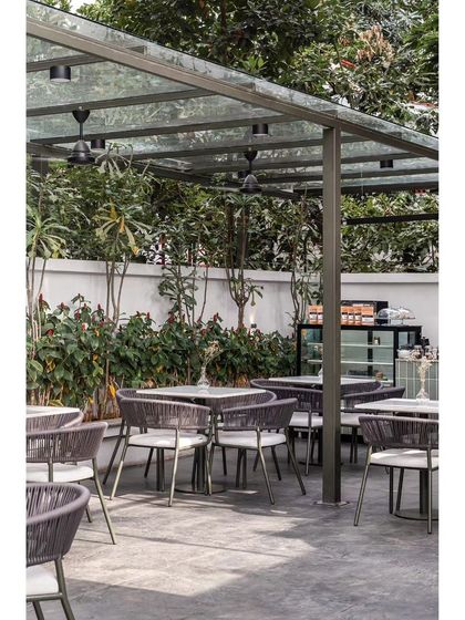 Another perspective of the outdoor seating, showing the simple yet sophisticated olive green metal and grey rope furniture. The design creates a tranquil escape from the urban environment.