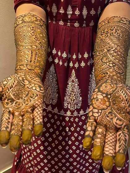 A stunningly detailed bridal design shown with palms open. The patterns are symmetrical yet unique, filled with fine lines, dots, and shading to create depth.