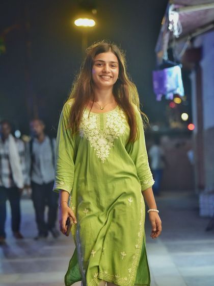 A full-length walking shot that captures the atmosphere of the bustling night market. This lifestyle portrait tells a story of exploring the city after dark.