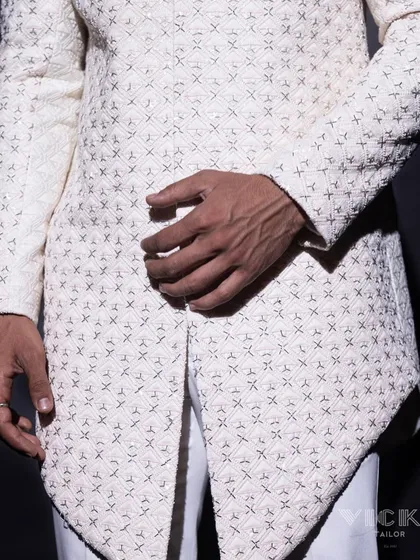 A detailed shot of the asymmetrical hem and fine embroidery of our white sherwani. Every angle is designed with intention and an eye for modern elegance.