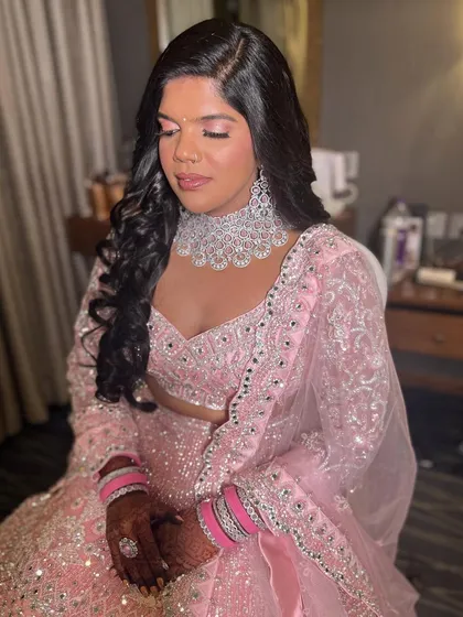 A stunning reception look in a pink lehenga. The makeup is glamorous and sophisticated, with a focus on the eyes.