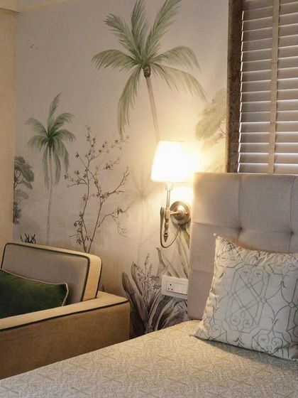 This angle shows how the nature-inspired wallpaper complements the room's furnishings. The design serves as a serene backdrop that ties together the textures of the armchair, bedding, and wooden blinds.