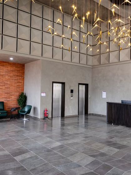 The main entrance lobby at Anthea Pharma, a 12,000 sq. ft. space combining industrial design with natural elements. The flooring is natural grey limestone, complemented by a brick-clad wall and microtopped exposed cement.