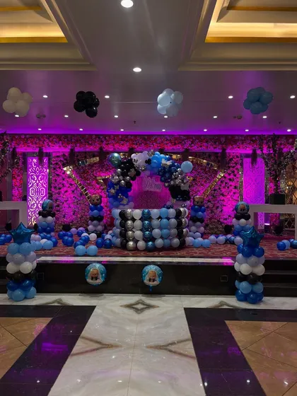 No space is too big to transform. Here is a full banquet hall decorated for a 'Welcome Baby' event, featuring a grand stage setup, multiple balloon pillars, and themed elements throughout the venue.