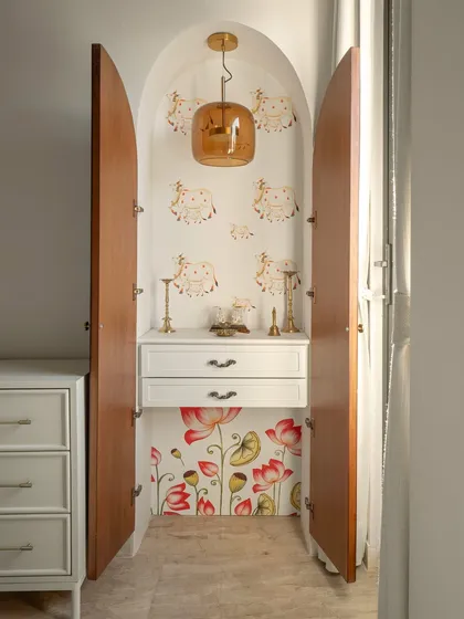 In this guest bedroom, I carved out an arched niche to house the mandir. The inside is adorned with beautiful, hand-painted wallpaper of lotuses and pichwai cows, creating a quiet spiritual pause.