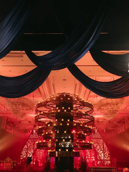 A massive, tiered candle structure served as a dramatic centerpiece for the sangeet stage. Under deep blue drapes and red lighting, it created a powerful focal point that was both grand and mesmerizing.