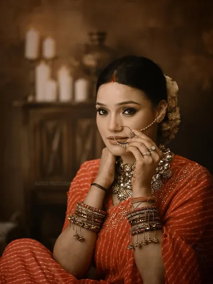 A powerful studio portrait of a woman in traditional attire, looking directly at the camera. The warm, dramatic lighting enhances the mood.