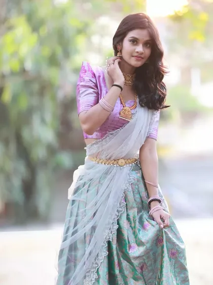 A three-quarter shot from the pastel half-saree series. The model's pose is graceful and showcases the beautiful gold jewellery.