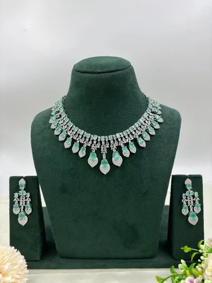 A silver-toned necklace with leaf-shaped mint-green stones.