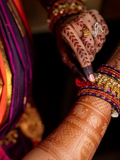 Here, the bride adjusts her bangles, giving a glimpse of the detailed band work on her wrist and the delicate leafy vines on the back of her hand.