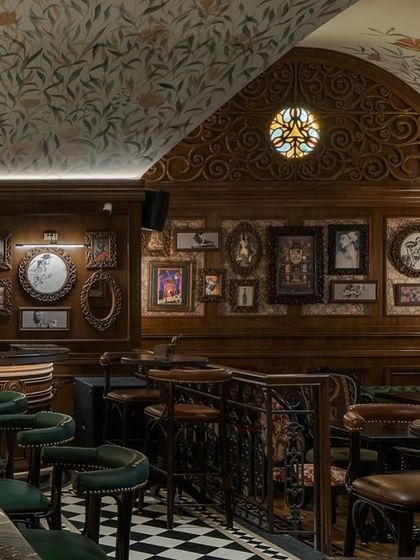 The interior of 'Sally by 1522' pub is rich with detail, featuring dark wood paneling, a gallery wall of quirky art, and custom-upholstered seating.