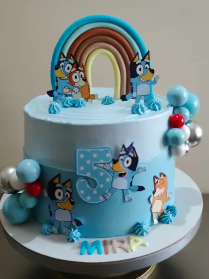 A Bluey themed cake for a 5th birthday! This design features the Heeler family under a fondant rainbow, ready for a party.
