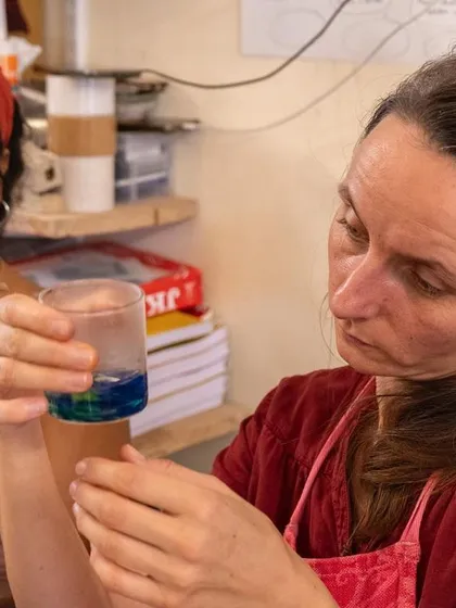 A participant examining the vibrant colors separating in a glass during our botanical ink extraction process. It's a moment of scientific discovery and artistic wonder as pigments are revealed.